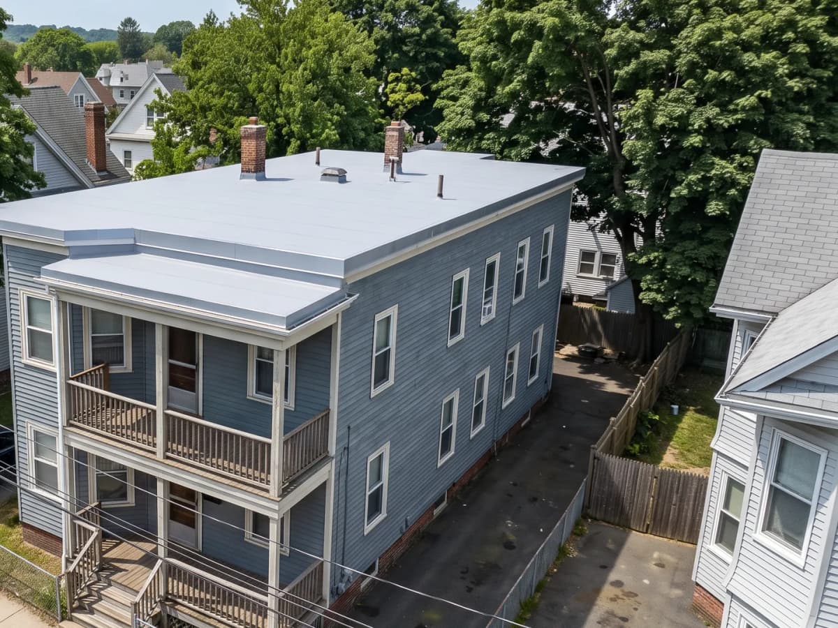 Multi-family house in an older Springfield-area neighborhood with a new light-gray low-slope membrane roof and stacked porches
